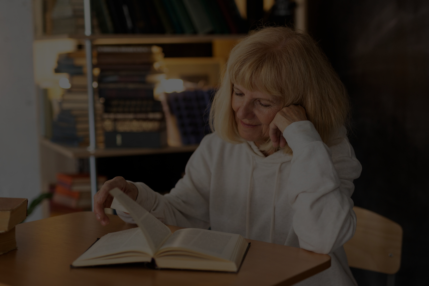 imagen de una mujer leyendo plácidamente un libro en lo que parece ser una biblioteca o espacio de lectura